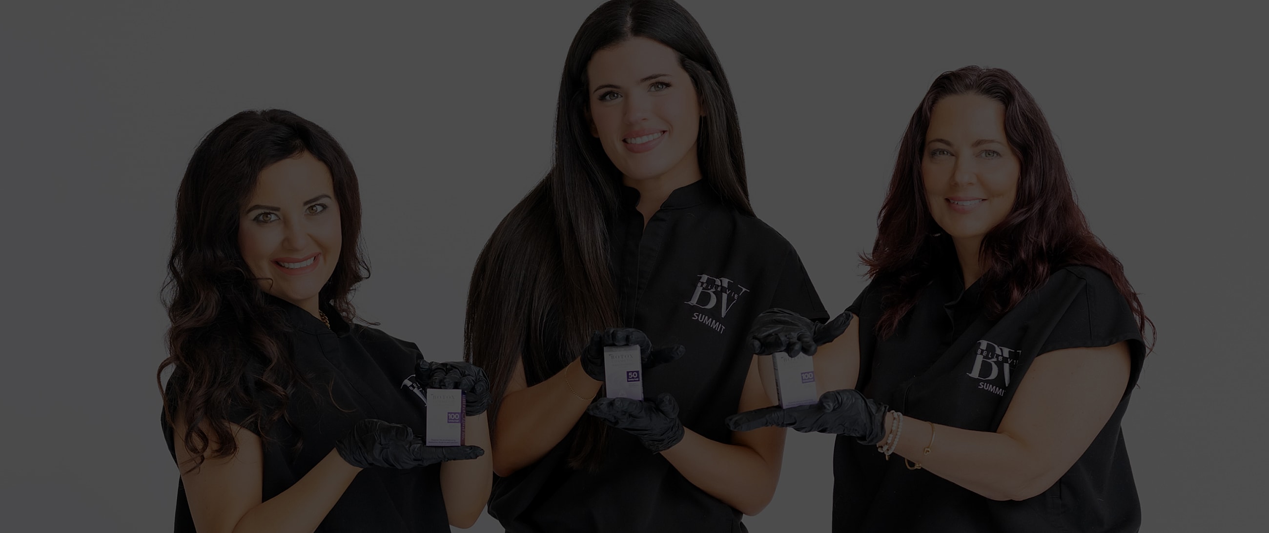 Three women holding beauty products, smiling.