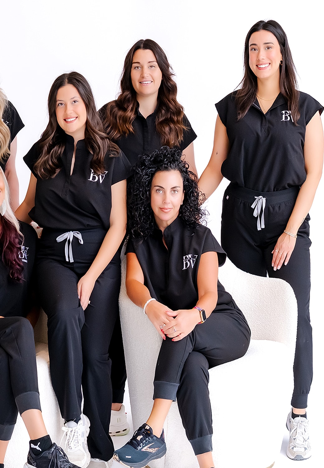 Group of women in matching black outfits posing.