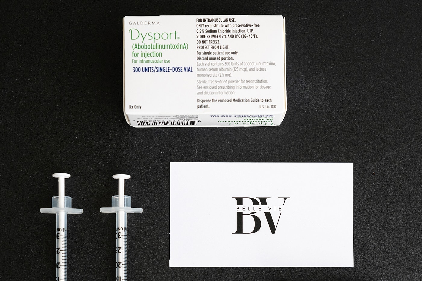 Dysport injection vial and syringes on table.