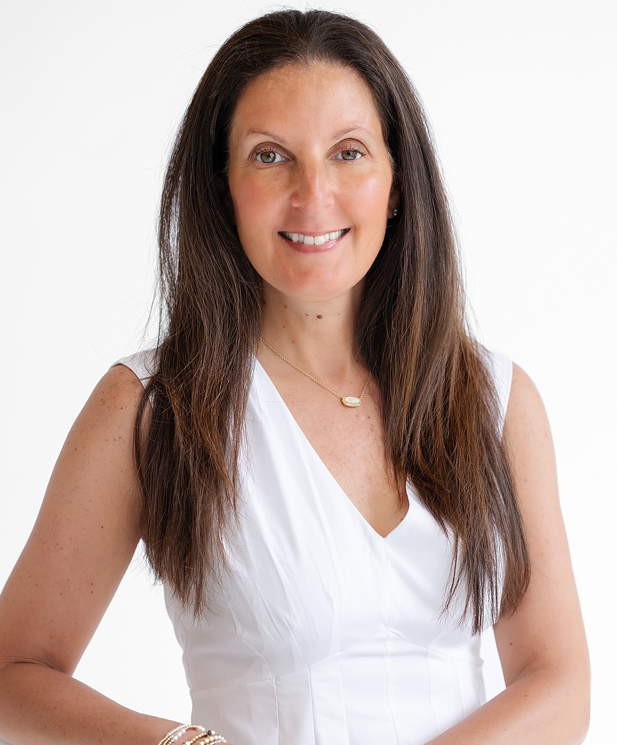 Smiling woman in white dress against plain background.