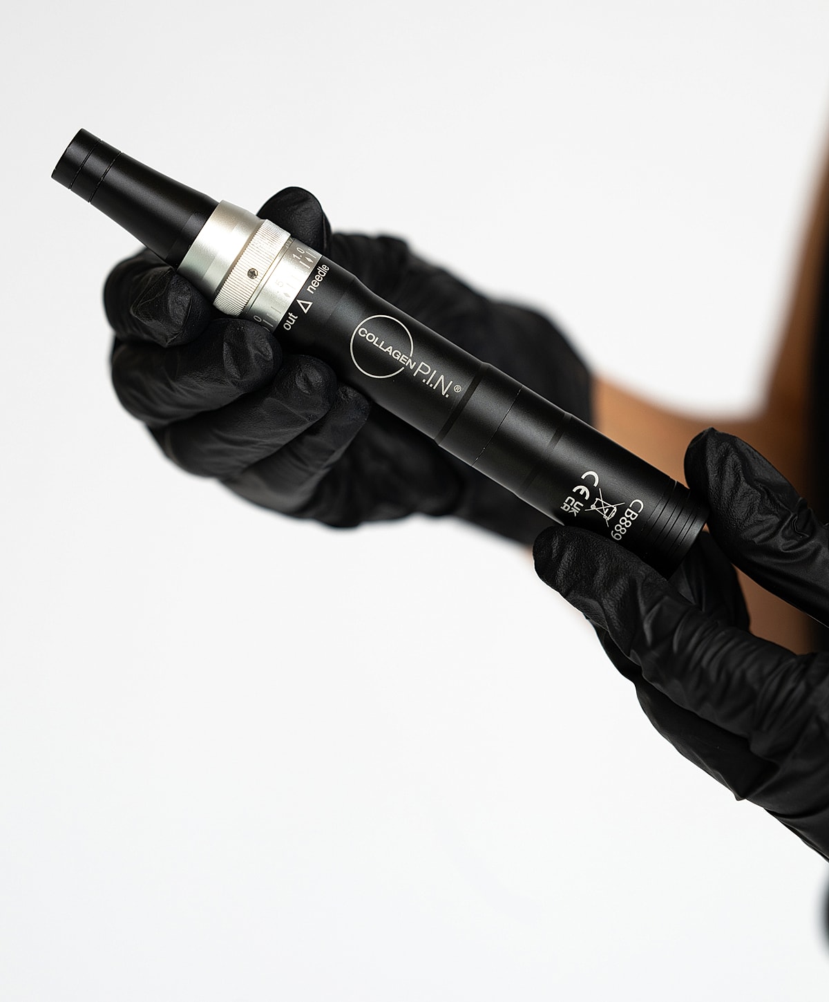 Hand holding a collagen microneedling pen.