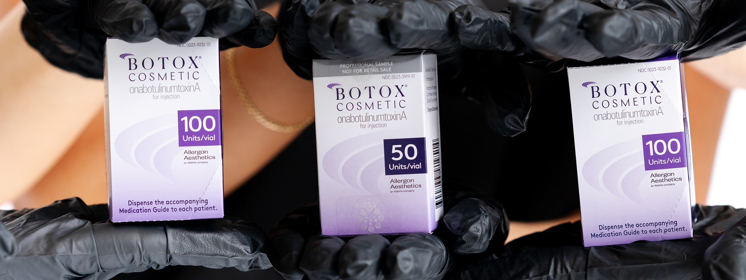 Botox vials in gloved hands, varying unit sizes.
