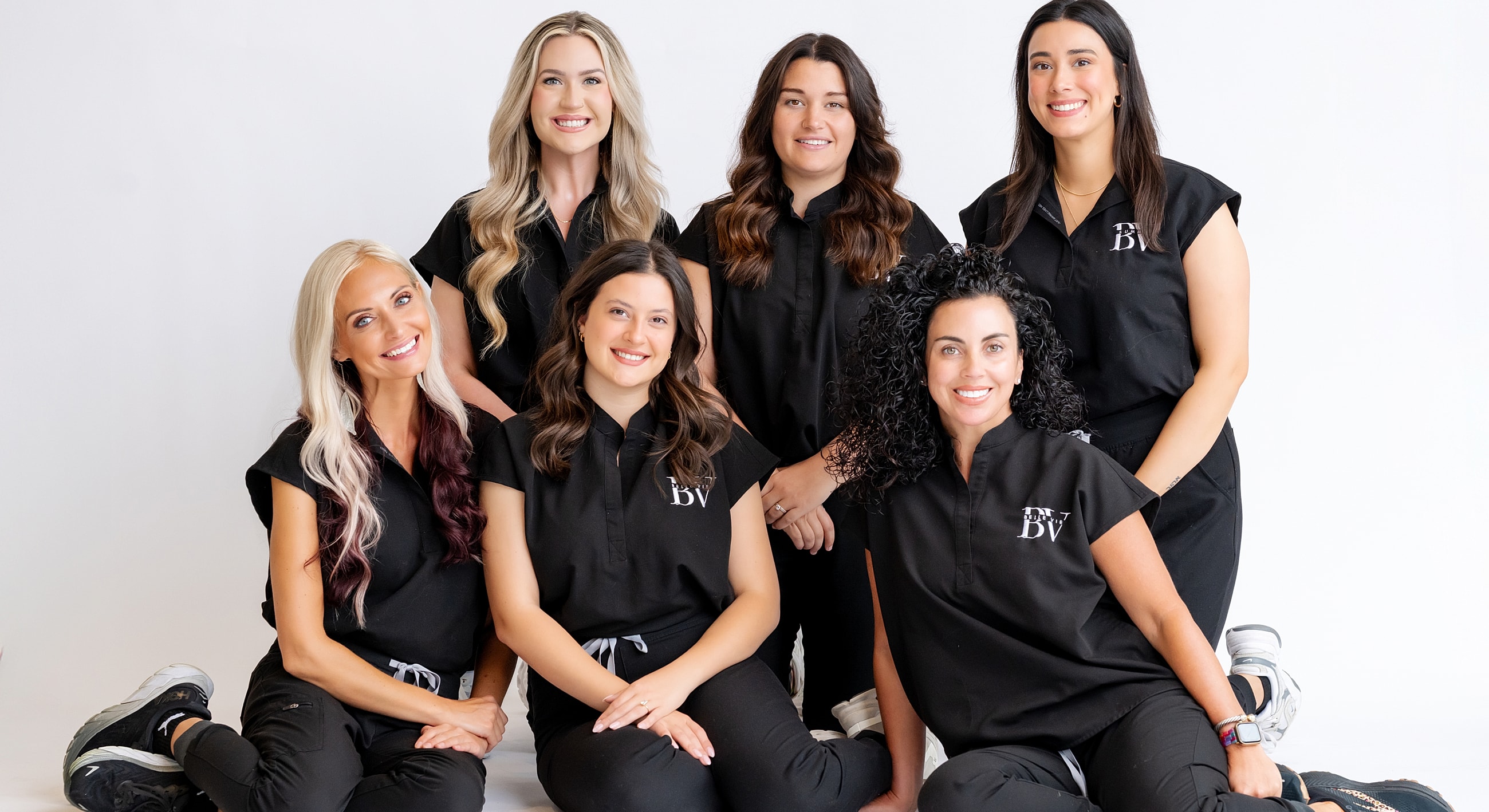 Team of women posing in black outfits.