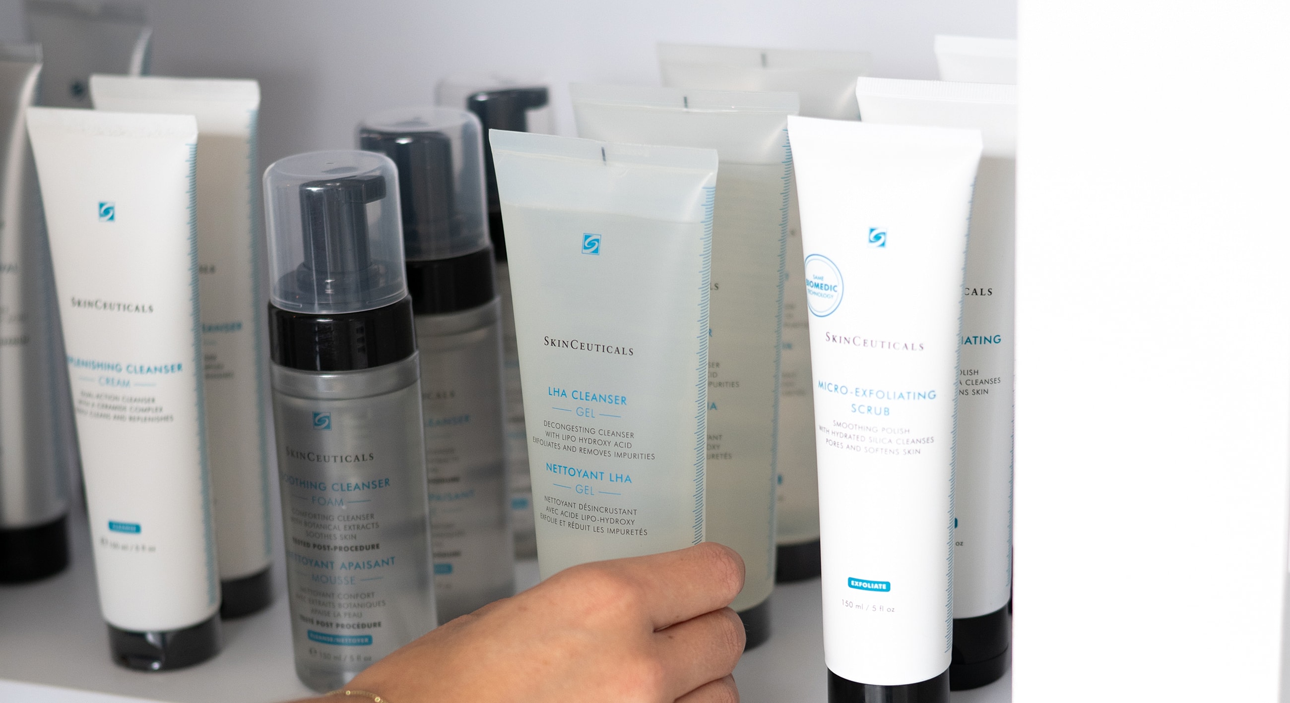 Skincare products on a shelf with a hand.